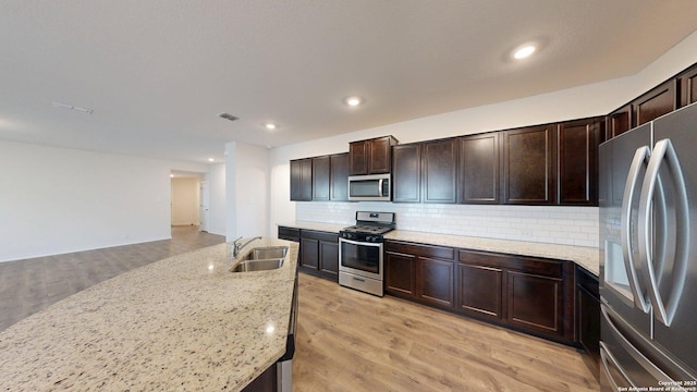 4219 Laterite Trl, San Antonio, TX 78253 - kitchen with appliances with stainless steel finishes, a sink, tasteful backsplash, light wood-type flooring, and dark brown cabinets