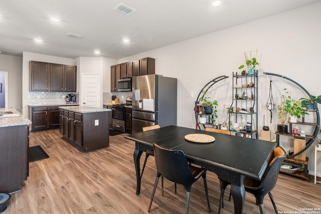 2079 Chelsea Grv, New Braunfels, TX 78130 - kitchen with stainless steel appliances, dark brown cabinets, a center island, light wood finished floors, and recessed lighting