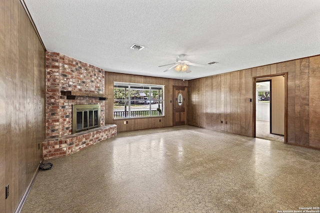 1706 Hickory St, Floresville, TX 78114 - unfurnished living room with a ceiling fan, wooden walls, a textured ceiling, and a fireplace