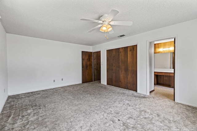 1706 Hickory St, Floresville, TX 78114 - unfurnished bedroom featuring carpet, multiple closets, a textured ceiling, ensuite bathroom, and a ceiling fan
