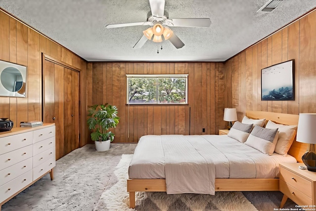 1706 Hickory St, Floresville, TX 78114 - bedroom with wooden walls, a textured ceiling, light colored carpet, and ceiling fan