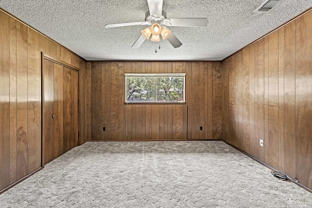 1706 Hickory St, Floresville, TX 78114 - unfurnished bedroom featuring carpet flooring, wood walls, a textured ceiling, a ceiling fan, and a closet