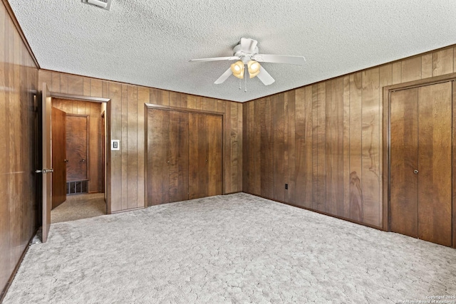 1706 Hickory St, Floresville, TX 78114 - unfurnished bedroom with a textured ceiling, wood walls, carpet flooring, and ceiling fan