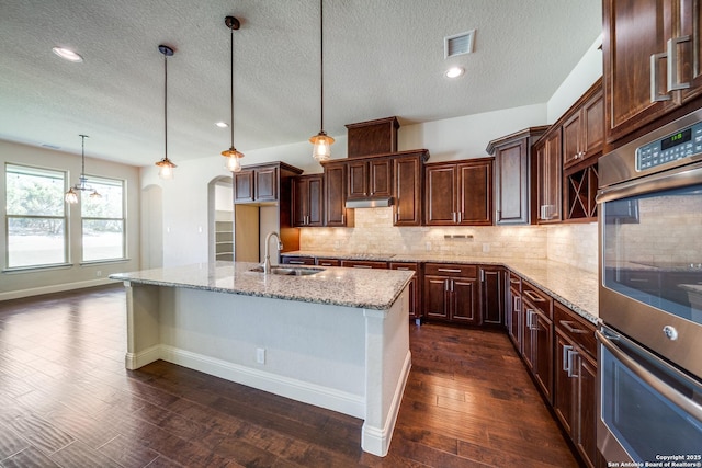 1703 Slumber Pass, San Antonio, TX 78260 - kitchen with a sink, stainless steel double oven, arched walkways, a textured ceiling, and dark wood-style floors