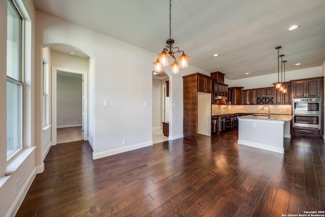 1703 Slumber Pass, San Antonio, TX 78260 - kitchen with arched walkways, a sink, double oven, decorative backsplash, and light stone counters