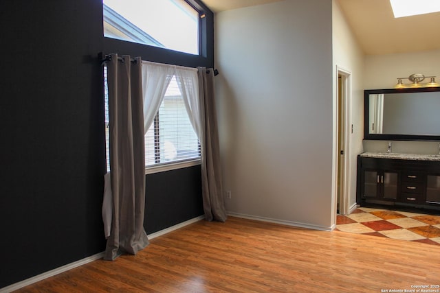11815 Vance Jackson Unit 301, San Antonio, TX 78230 - unfurnished room with a skylight, light wood finished floors, baseboards, a sink, and vaulted ceiling