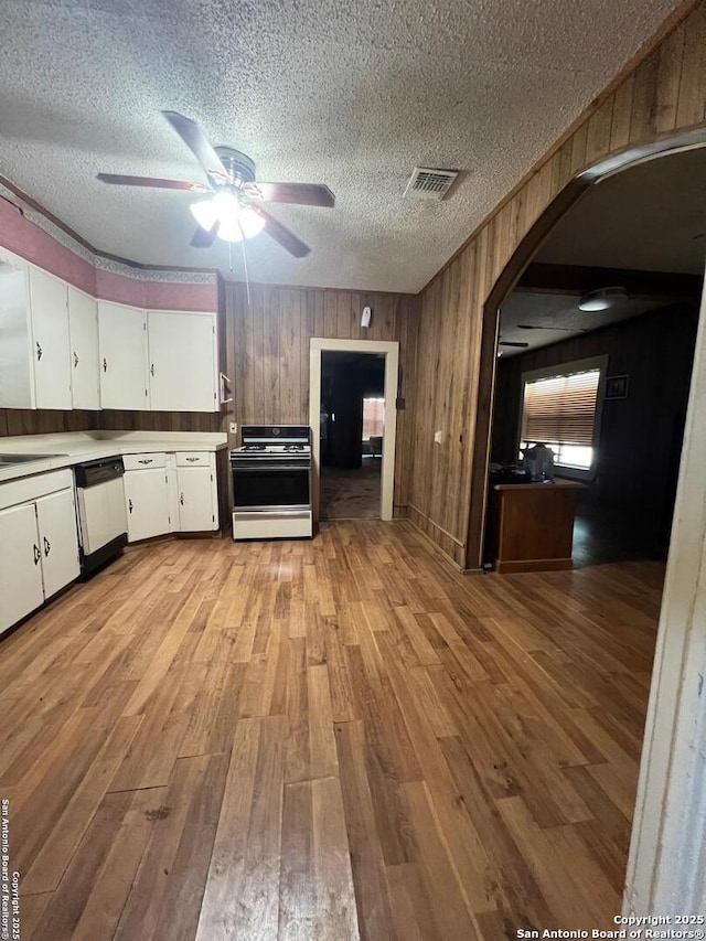 413 4th St, Poteet, TX 78065 - kitchen featuring white appliances, arched walkways, light wood-style floors, white cabinets, and a ceiling fan