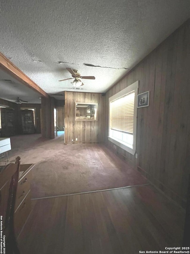 413 4th St, Poteet, TX 78065 - unfurnished living room with a ceiling fan, wood walls, wood finished floors, and a textured ceiling