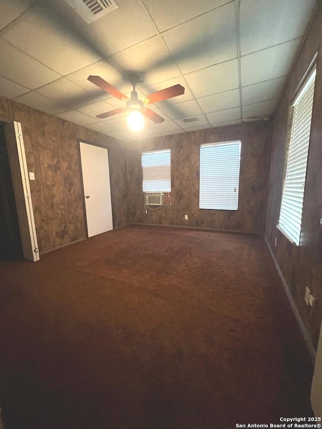 413 4th St, Poteet, TX 78065 - empty room with plenty of natural light, a drop ceiling, wood walls, a ceiling fan, and carpet flooring