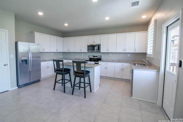 10322 Lady Bird, San Antonio, TX 78252 - kitchen featuring stainless steel appliances, a center island, white cabinets, a breakfast bar, and light stone countertops