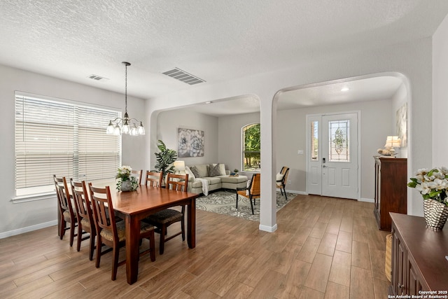 116 Cold Riv, Boerne, TX 78006 - dining space featuring arched walkways, light wood finished floors, a chandelier, and a textured ceiling