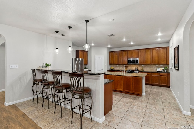 116 Cold Riv, Boerne, TX 78006 - kitchen with appliances with stainless steel finishes, arched walkways, brown cabinets, a peninsula, and a breakfast bar area
