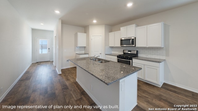 21006 Watercourse Way, San Antonio, TX 78266 - kitchen featuring gas stove, stainless steel microwave, a kitchen island with sink, backsplash, and dark wood-style flooring