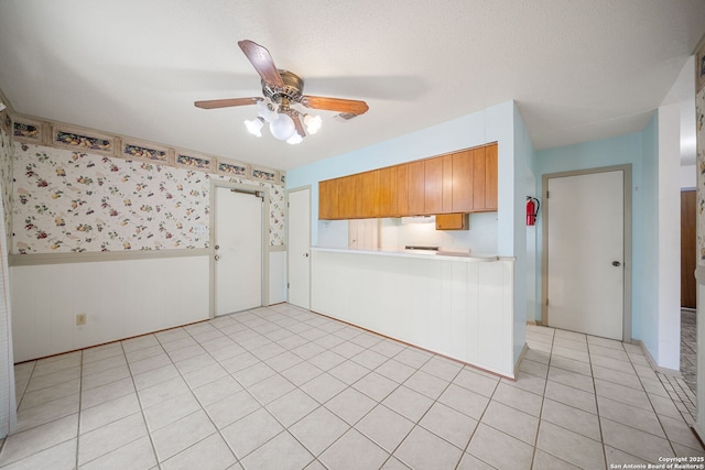 7022 Centergrove Dr, San Antonio, TX 78227 - kitchen featuring wainscoting, ceiling fan, light countertops, a peninsula, and brown cabinets