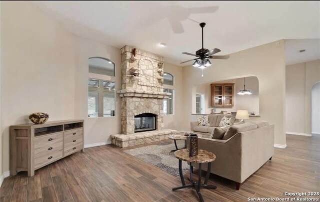 30184 Bridlegate, Bulverde, TX 78163 - living room with arched walkways, ceiling fan, wood finished floors, and a stone fireplace