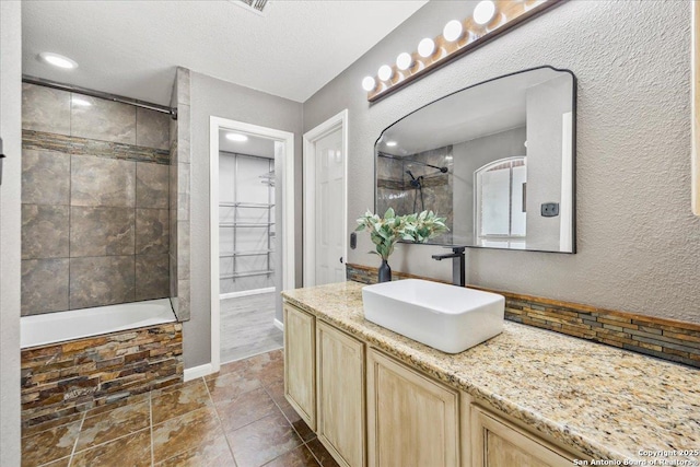 3607 Mill Mdw, San Antonio, TX 78247 - bathroom with vanity, a textured wall, tiled shower / bath combo, and a spacious closet