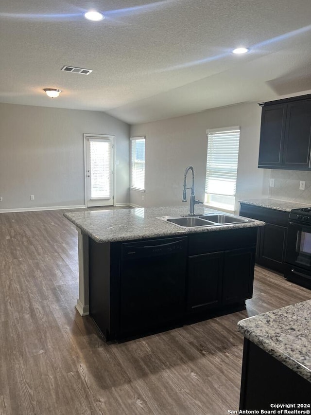 2649 Mccrae, New Braunfels, TX 78130 - kitchen with black appliances, open floor plan, an island with sink, wood finished floors, and dark cabinetry