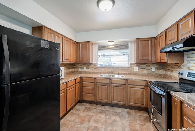 5707 Bogart, San Antonio, TX 78240 - kitchen with stainless steel electric stove, freestanding refrigerator, under cabinet range hood, and brown cabinets