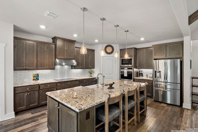744 E Rio Azule, Pipe Creek, TX 78063 - kitchen with stainless steel appliances, under cabinet range hood, dark brown cabinetry, dark wood-style floors, and recessed lighting