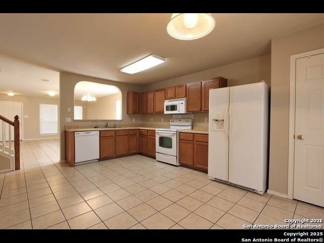 10235 Crystal, Universal City, TX 78148 - kitchen featuring white appliances, light countertops, a chandelier, light tile patterned flooring, and brown cabinetry