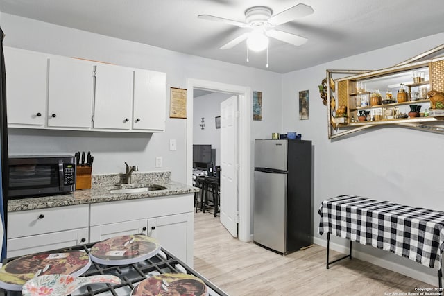 1105 Delgado St, San Antonio, TX 78207 - kitchen featuring freestanding refrigerator, white cabinetry, light wood-type flooring, and ceiling fan