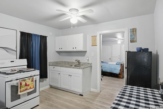 1105 Delgado St, San Antonio, TX 78207 - kitchen featuring white range with gas stovetop, ceiling fan, freestanding refrigerator, white cabinets, and light wood-style flooring
