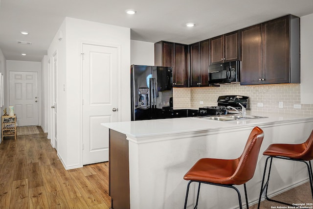 175 Amber, Maxwell, TX 78656 - kitchen with black appliances, dark brown cabinetry, light wood-type flooring, a peninsula, and a kitchen breakfast bar
