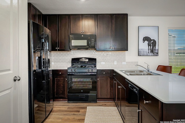 175 Amber, Maxwell, TX 78656 - kitchen with black appliances, a peninsula, light wood-style floors, and tasteful backsplash