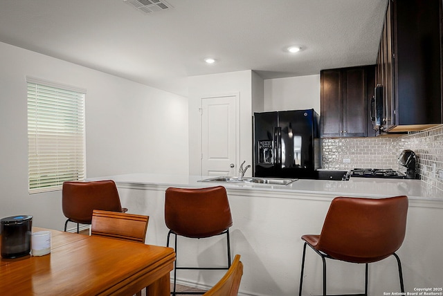 175 Amber, Maxwell, TX 78656 - kitchen with black fridge with ice dispenser, range, backsplash, light countertops, and a breakfast bar