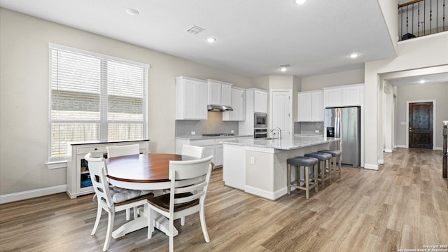107 Destiny, Boerne, TX 78006 - kitchen with stainless steel appliances, under cabinet range hood, white cabinetry, an island with sink, and recessed lighting