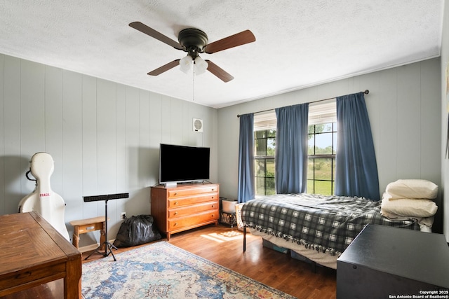 1373 County Road 373, Uvalde, TX 78801 - bedroom with wood finished floors, ceiling fan, a textured ceiling, and a decorative wall
