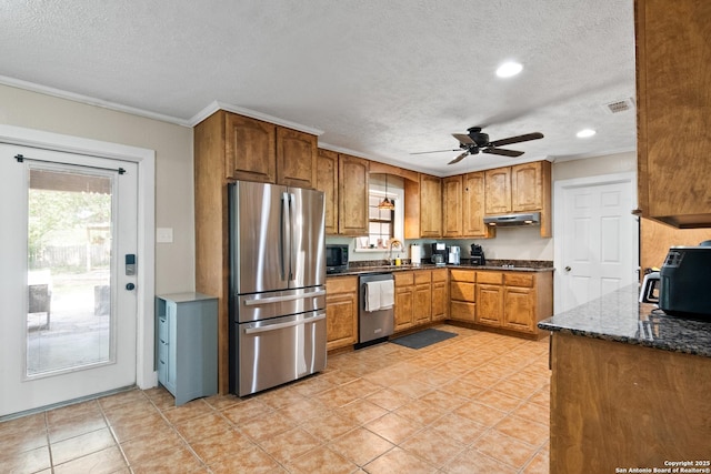 1373 County Road 373, Uvalde, TX 78801 - kitchen with appliances with stainless steel finishes, under cabinet range hood, a textured ceiling, brown cabinetry, and a ceiling fan