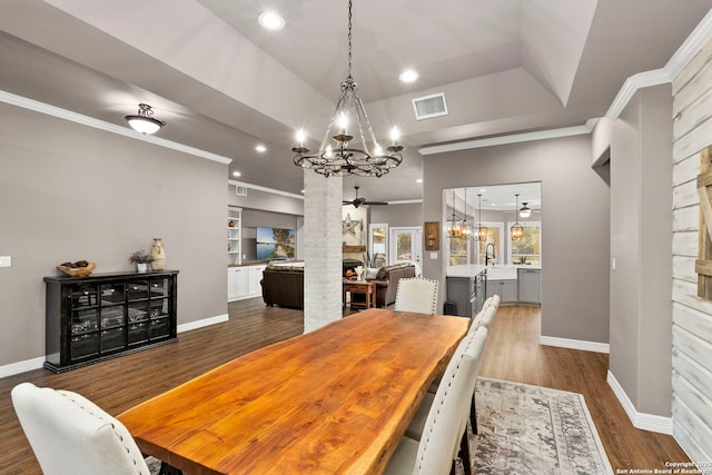 608 Kendall Pkwy, Boerne, TX 78015 - dining space with a large fireplace, a ceiling fan, a chandelier, wood finished floors, and ornamental molding