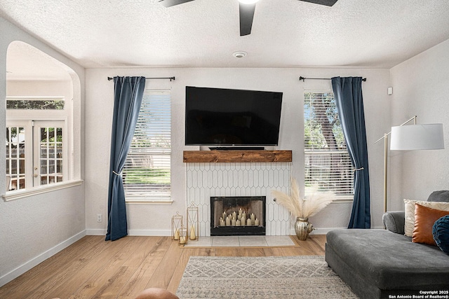 13812 Riverbank Pass, Helotes, TX 78023 - living area with wood finished floors, a textured ceiling, ceiling fan, arched walkways, and a fireplace with flush hearth