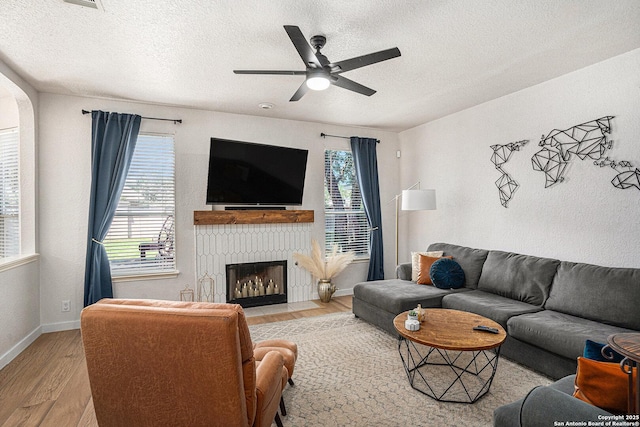 13812 Riverbank Pass, Helotes, TX 78023 - living room with wood finished floors, a textured ceiling, plenty of natural light, ceiling fan, and a fireplace with flush hearth