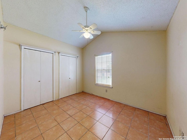 3415 Twining, San Antonio, TX 78211 - unfurnished bedroom with two closets, vaulted ceiling, ceiling fan, light tile patterned floors, and a textured ceiling