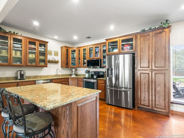 1131 Meadow Stream Rd, Spring Branch, TX 78070 - kitchen with appliances with stainless steel finishes, brown cabinetry, concrete floors, recessed lighting, and light stone countertops