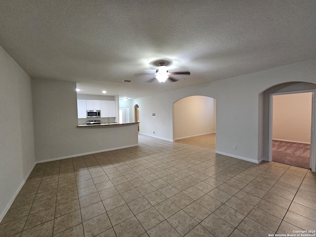 6723 Luckey Pond, San Antonio, TX 78252 - unfurnished living room featuring arched walkways, ceiling fan, light tile patterned flooring, and a textured ceiling