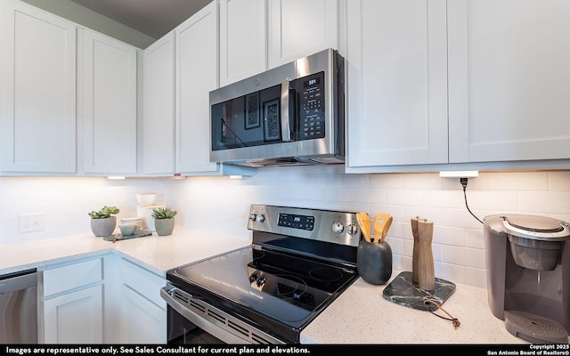 14732 Sycamore Xing, San Antonio, TX 78252 - kitchen with appliances with stainless steel finishes, tasteful backsplash, white cabinets, and light stone countertops