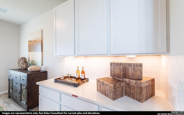 14732 Sycamore Xing, San Antonio, TX 78252 - kitchen with light stone counters, white cabinets, decorative backsplash, and light wood finished floors