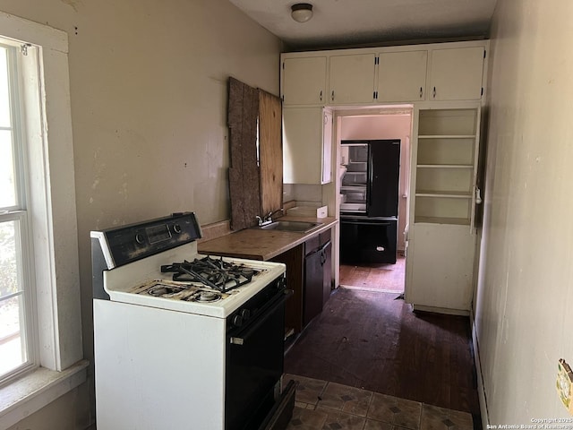 310 N Gevers, San Antonio, TX 78202 - kitchen featuring white gas range oven, white cabinets, light countertops, freestanding refrigerator, and dark wood-type flooring