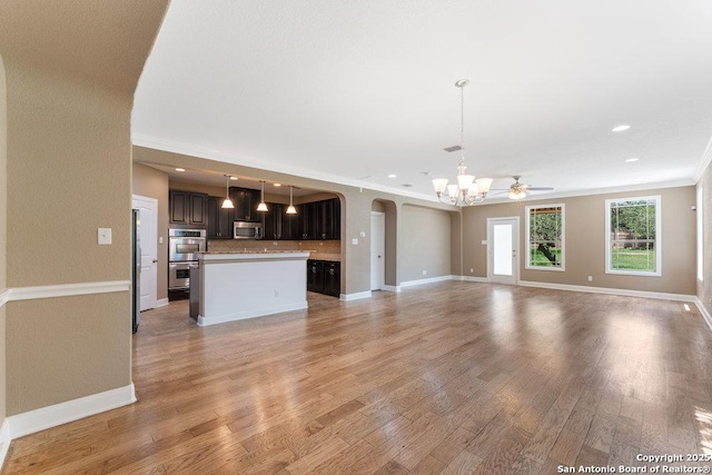 120 Red Bud, Boerne, TX 78006 - unfurnished living room featuring a chandelier, arched walkways, light wood-style flooring, crown molding, and recessed lighting