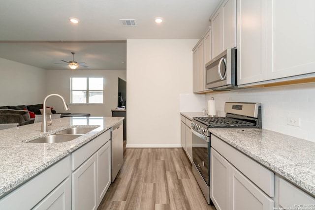 4951 Ranahan Pass, Saint Hedwig, TX 78152 - kitchen featuring stainless steel appliances, light wood-style floors, open floor plan, decorative backsplash, and ceiling fan