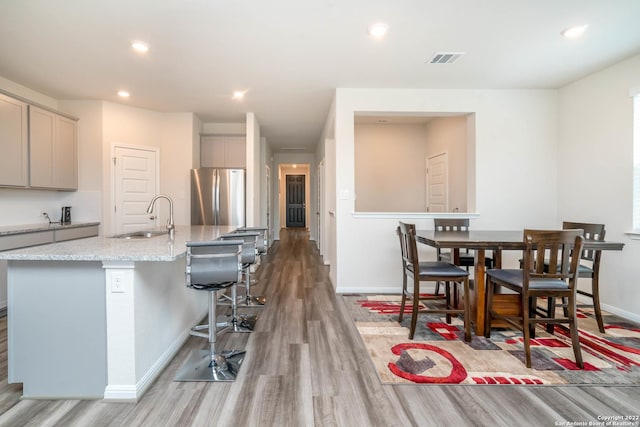 4951 Ranahan Pass, Saint Hedwig, TX 78152 - kitchen with freestanding refrigerator, gray cabinetry, light wood-style floors, light stone countertops, and recessed lighting