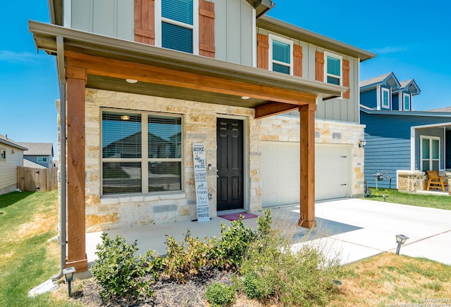 4951 Ranahan Pass, Saint Hedwig, TX 78152 - view of front of home with board and batten siding, stone siding, a garage, concrete driveway, and covered porch