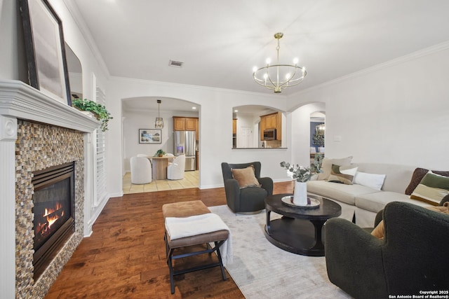 20907 Cactus Peak, San Antonio, TX 78258 - living area featuring arched walkways, a chandelier, a stone fireplace, crown molding, and dark wood-type flooring
