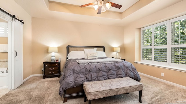 10522 Foxen, Helotes, TX 78023 - carpeted bedroom featuring a barn door, a tray ceiling, ensuite bathroom, and ceiling fan
