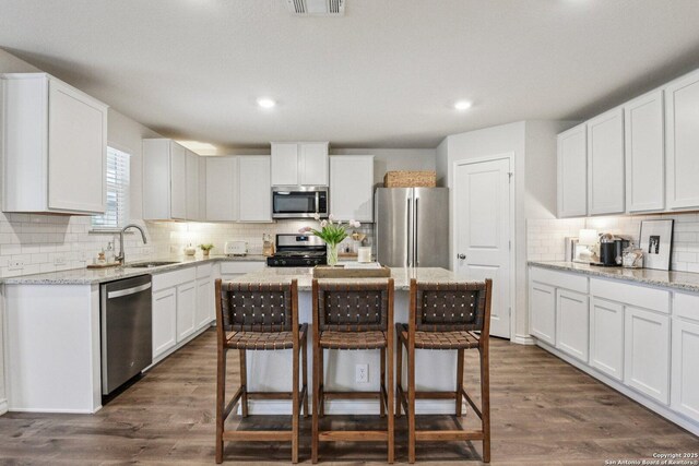 183 Amethyst Woodstar, San Antonio, TX 78253 - kitchen with appliances with stainless steel finishes, tasteful backsplash, white cabinetry, a kitchen bar, and dark wood-style flooring