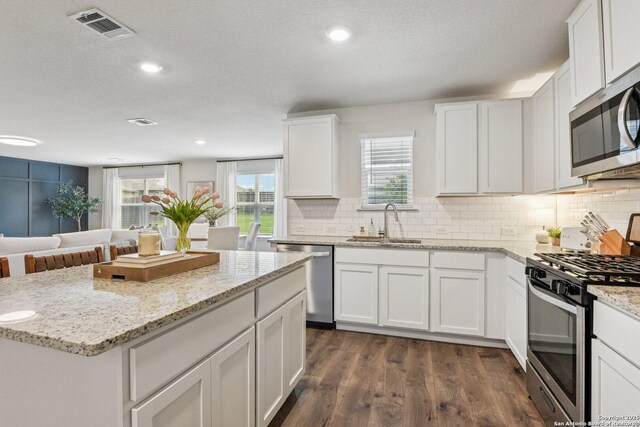 183 Amethyst Woodstar, San Antonio, TX 78253 - kitchen with appliances with stainless steel finishes, dark wood-type flooring, decorative backsplash, white cabinets, and a kitchen island