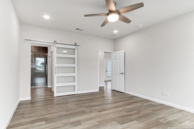 9911 Loma Alta Cir, Converse, TX 78109 - unfurnished bedroom featuring light wood-style flooring, recessed lighting, a barn door, and a ceiling fan